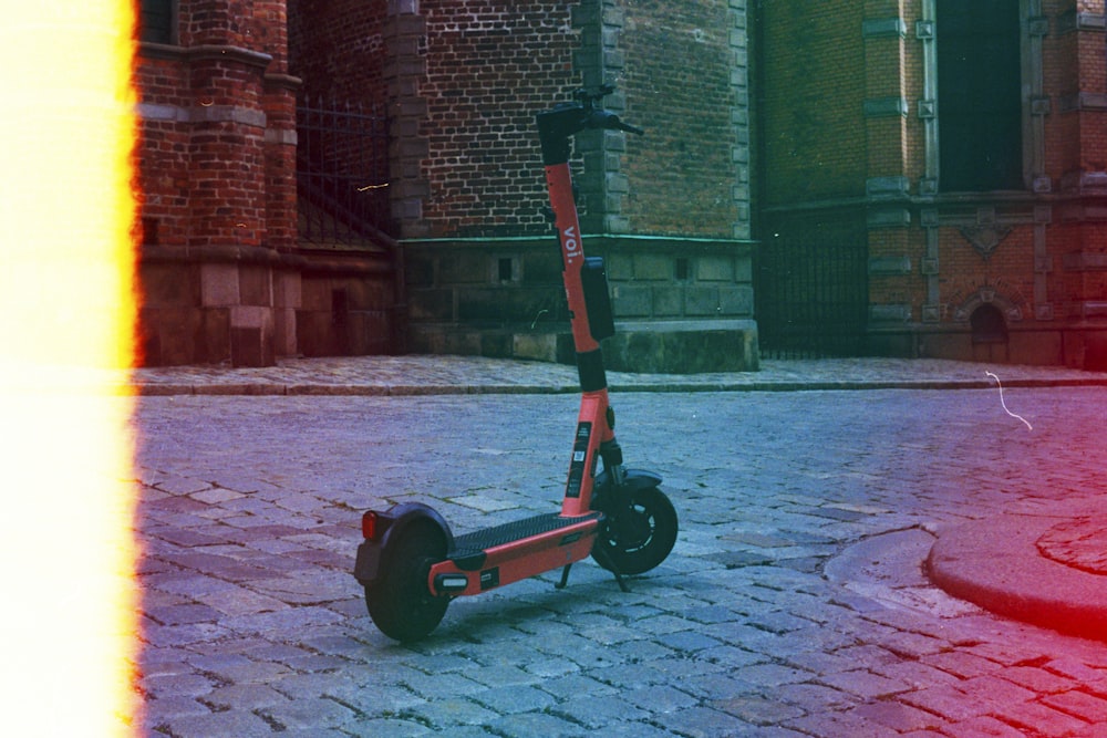 black and red kick scooter on brown concrete floor