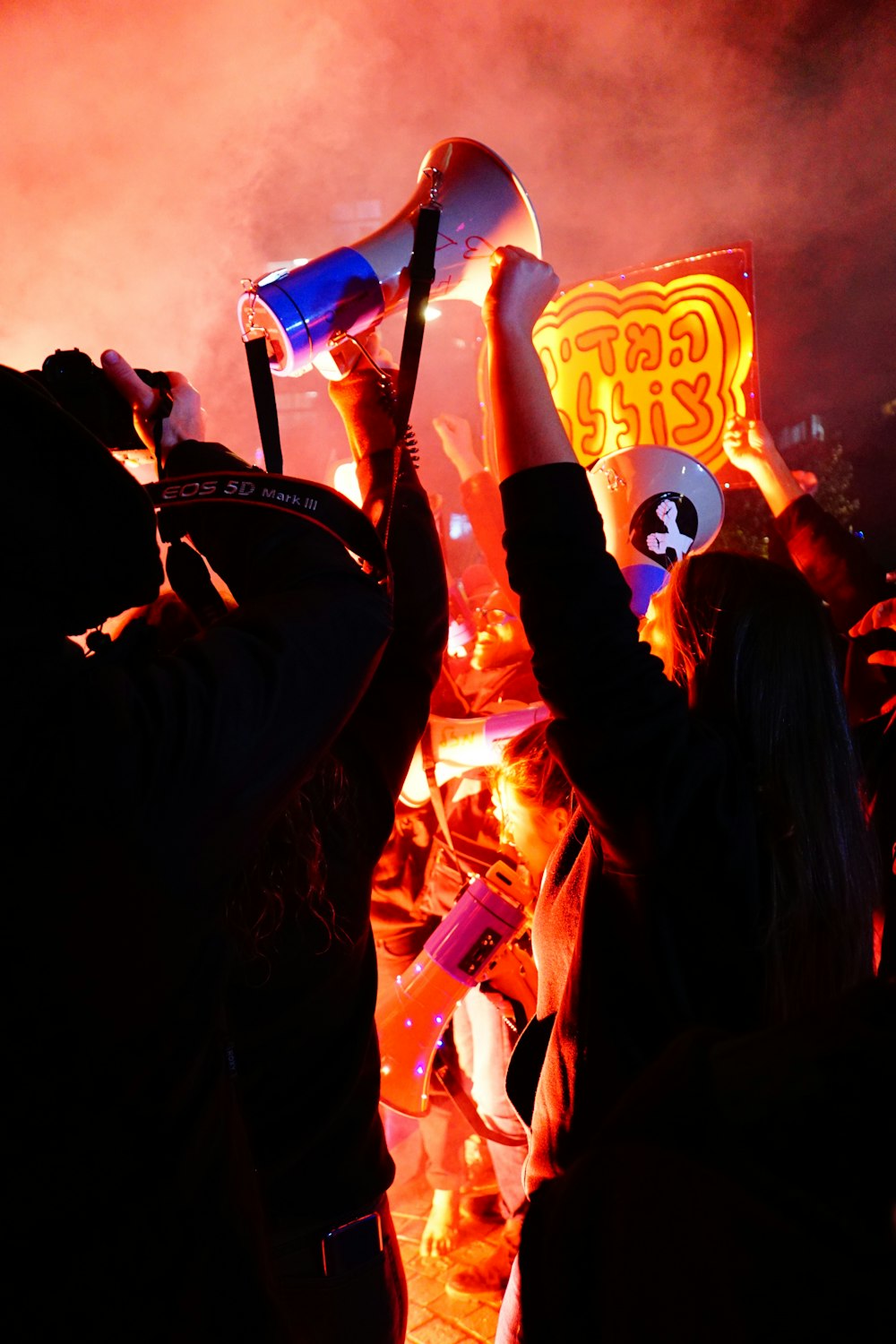 people raising hands with blue and red neon light signage