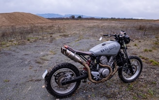 Image of a sleek desert scrambler motorcycle in a sandy landscape.