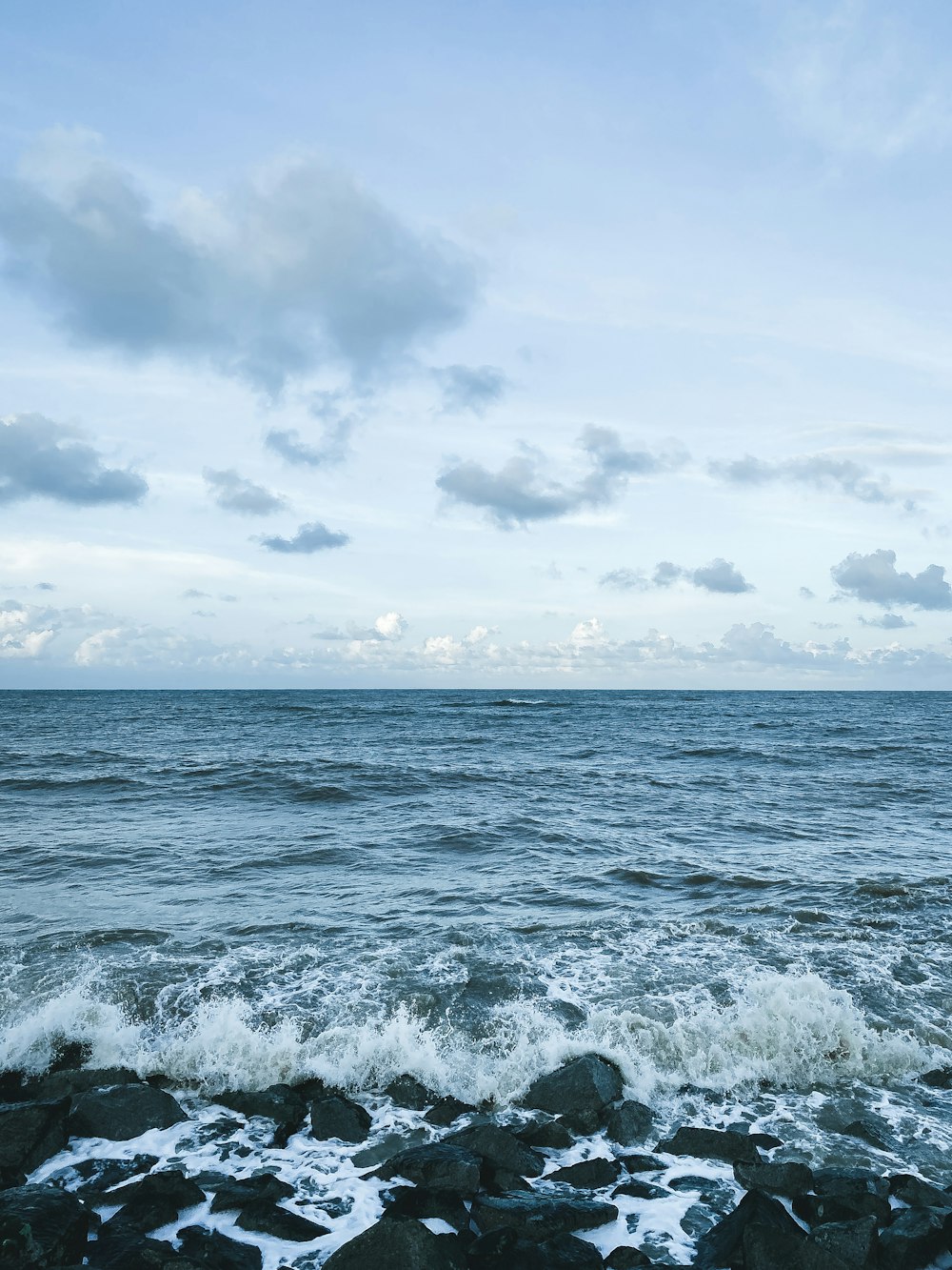 ocean waves under white clouds during daytime