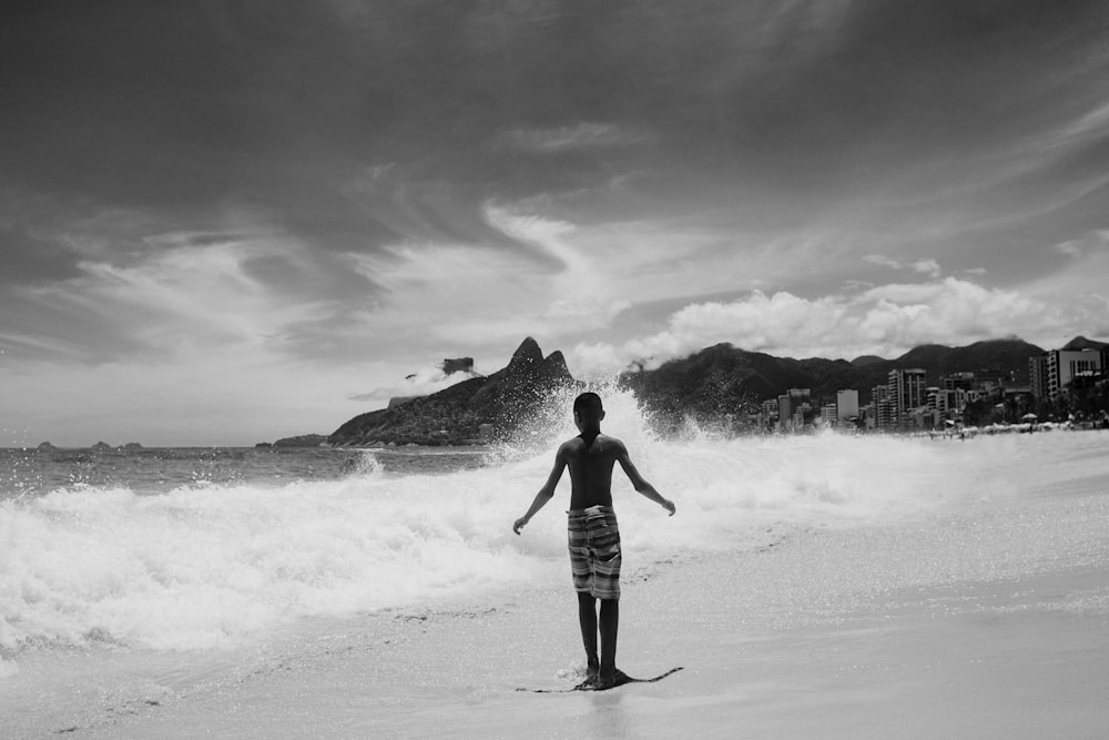 Foto in scala di grigi della donna che cammina sulla spiaggia