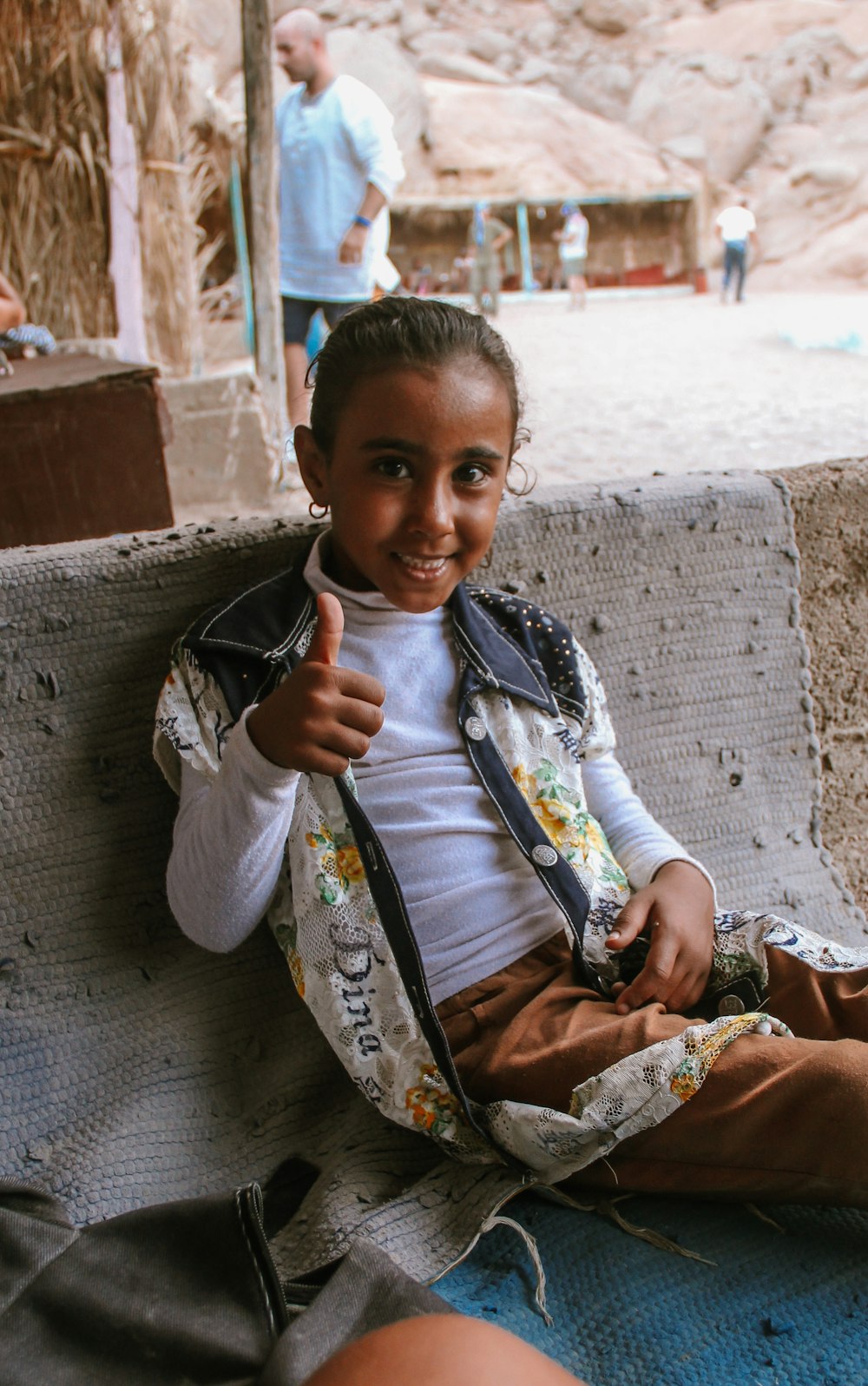 boy in white and blue long sleeve shirt sitting on brown and white floral textile