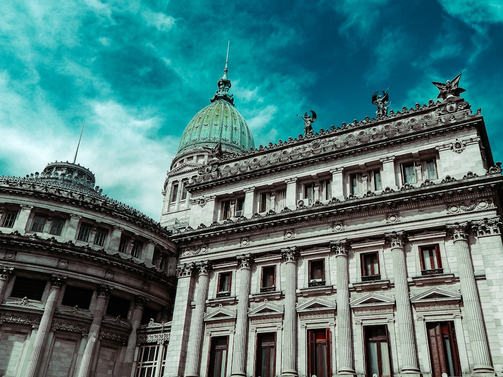 edificio de hormigón blanco bajo el cielo azul y las nubes blancas durante el día