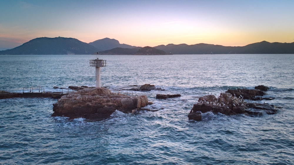 white and red lighthouse on brown rock formation near body of water during daytime