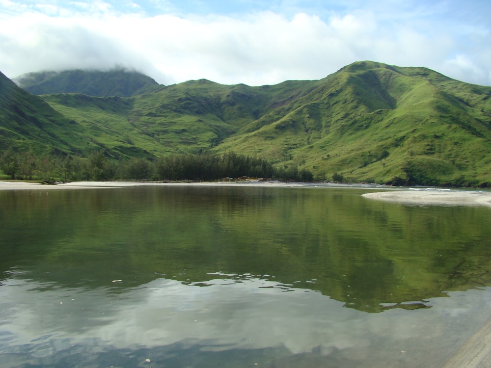 green mountains beside body of water during daytime