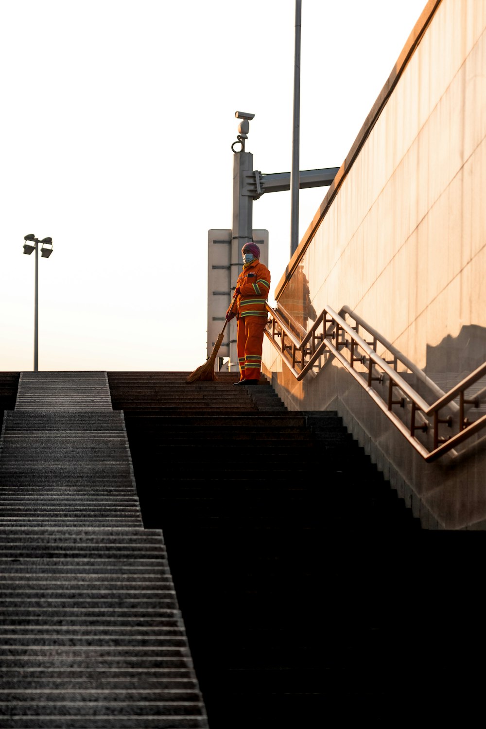 woman in orange jacket standing on black staircase