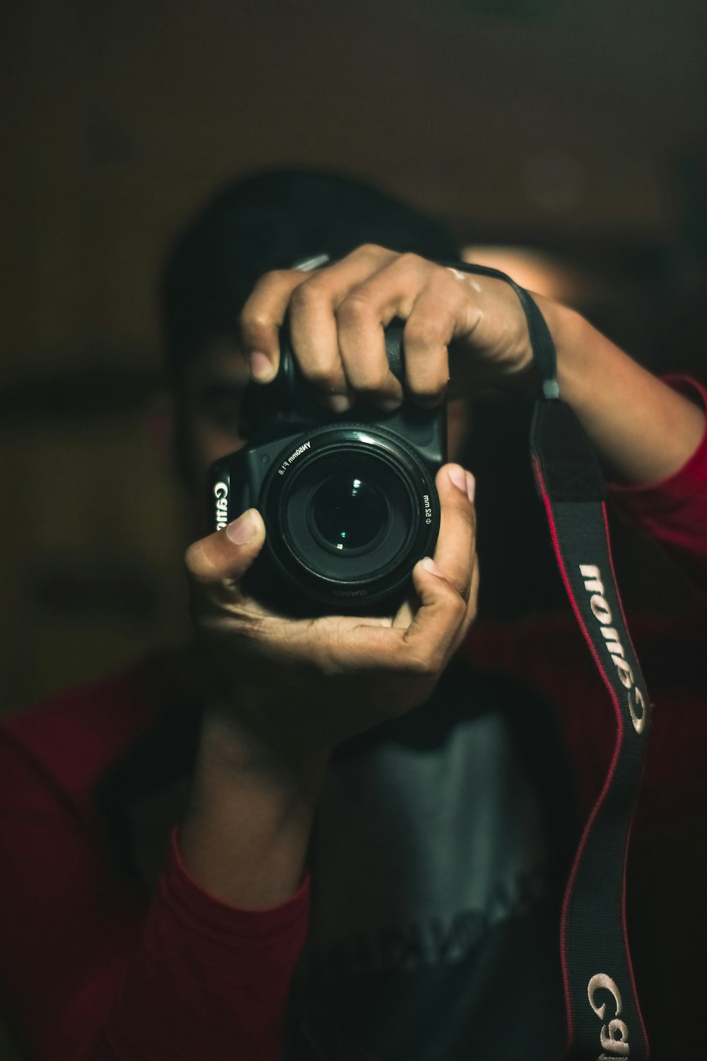 Persona che tiene in mano una fotocamera reflex digitale Canon nera