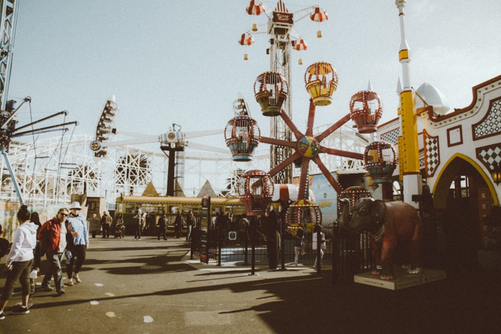 people walking on street near red and yellow ferris wheel during daytime