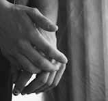 Sensual shot of intertwined hands wearing black leather gloves with subtle red accents.