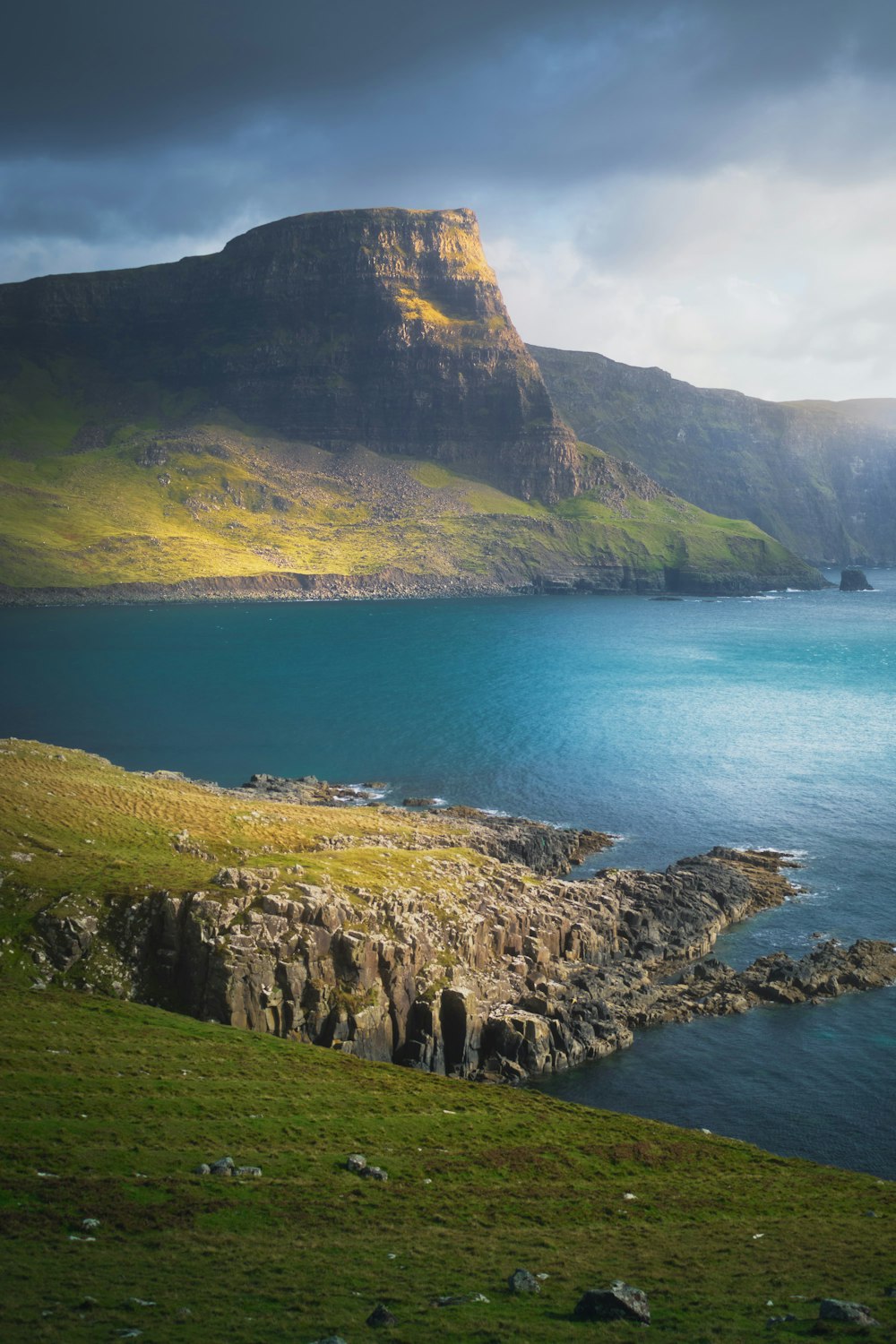 green and brown mountain beside blue sea during daytime