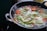 A close-up of a cast iron skillet with fresh vegetables sizzling inside.