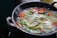 Close-up of a shiny stainless steel karahi with fresh vegetables cooking inside.