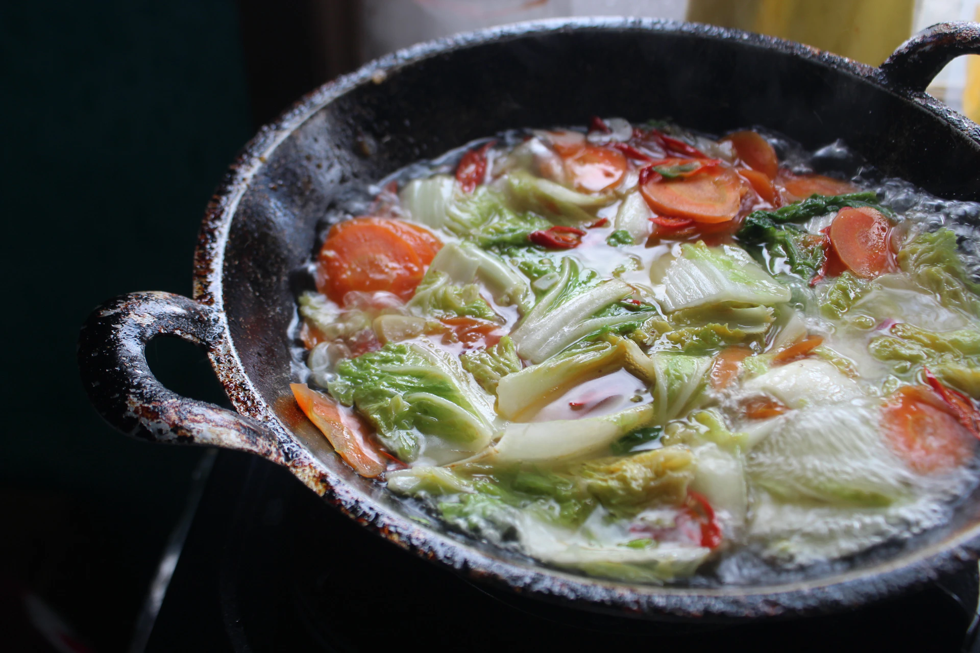 Close-up of a matte forest green cast iron skillet sizzling with fresh, vibrant vegetables, highlighting the rustic charm of home cooking.