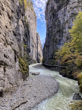 river between rocky mountains under blue sky during daytime