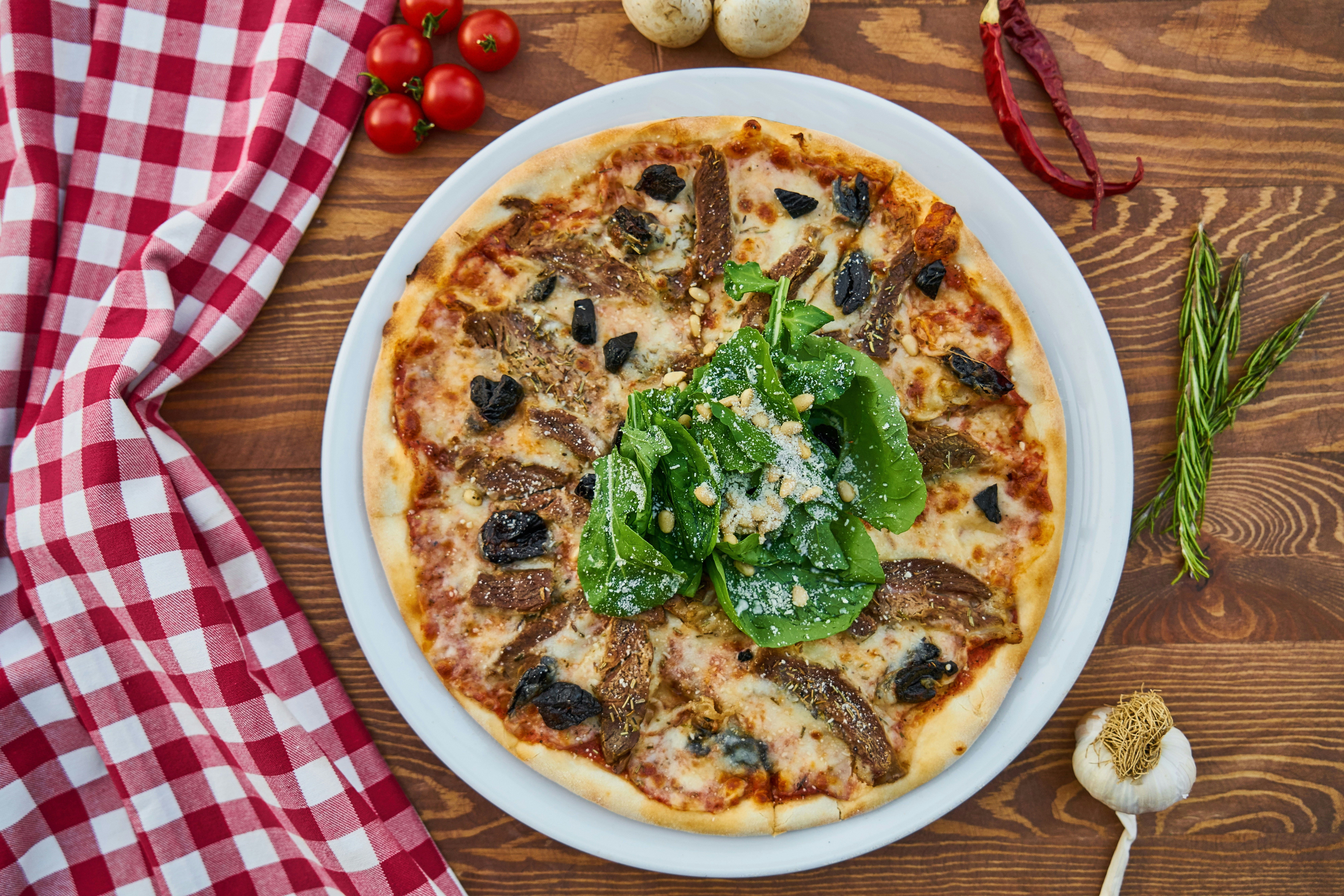 Pizza with greens on a plate beside a checked cloth