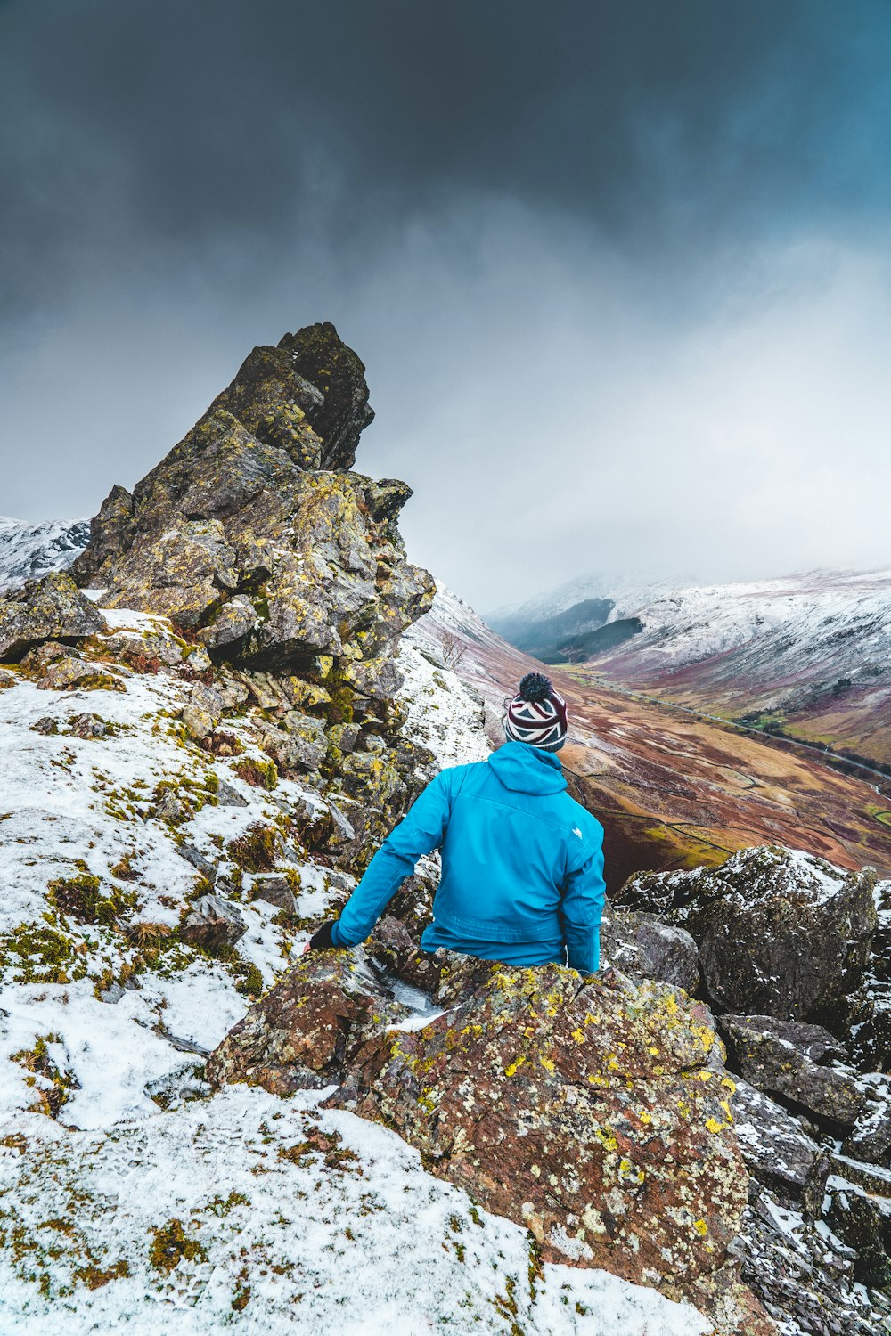 person in blue jacket standing on rocky mountain during daytime