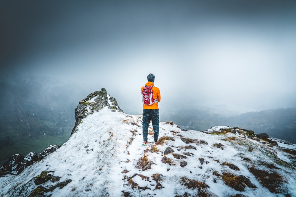 man in orange jacket standing on snow covered ground