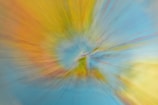 A colorful abstract image with a swirling effect that creates a vortex-like appearance. The center appears more defined, while the edges blur outward, suggesting motion.