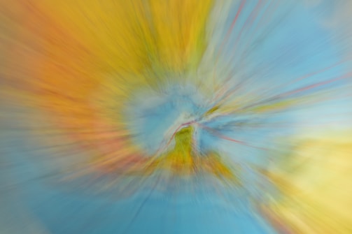 A colorful abstract image with a swirling effect that creates a vortex-like appearance. The center appears more defined, while the edges blur outward, suggesting motion.