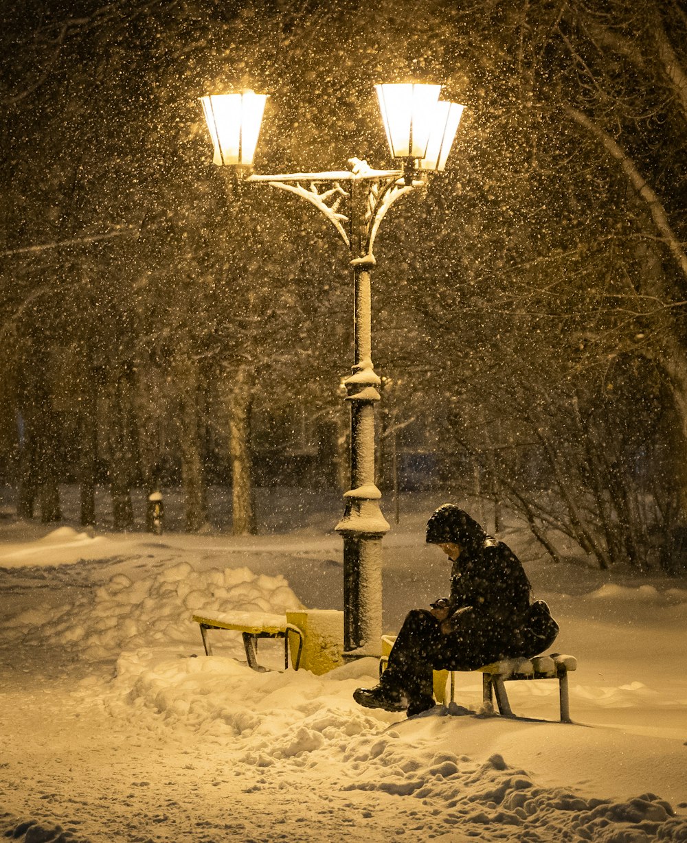 person sitting on chair near street light during night time
