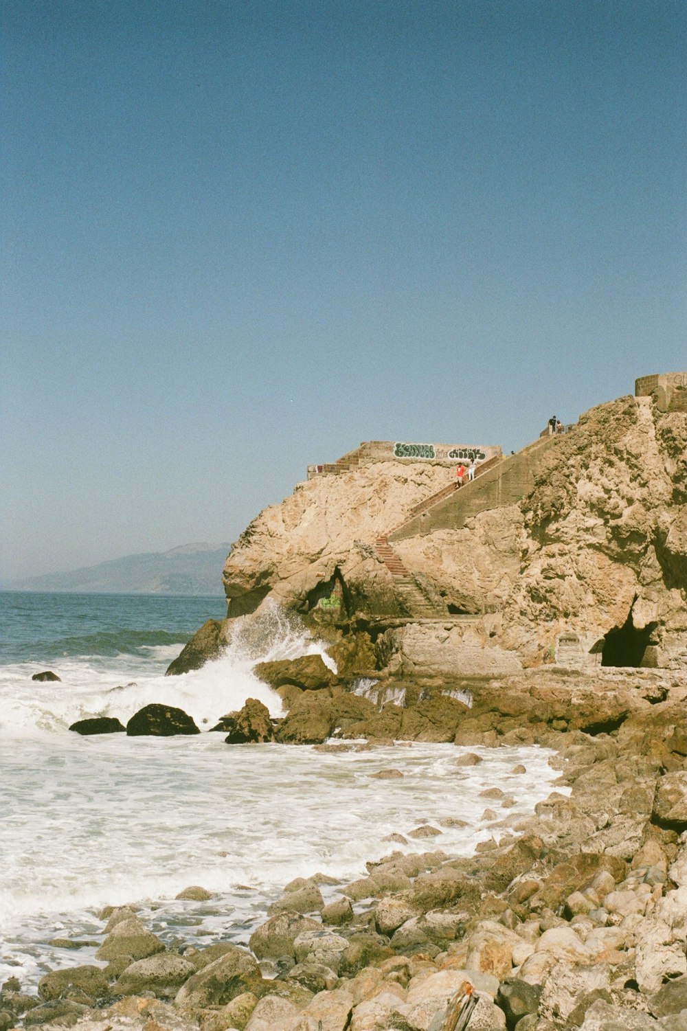 white and brown concrete building on brown rock formation near sea during daytime