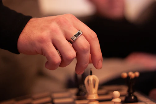 Hands shaking over a contract with a chessboard softly blurred behind, representing trust and agreement.