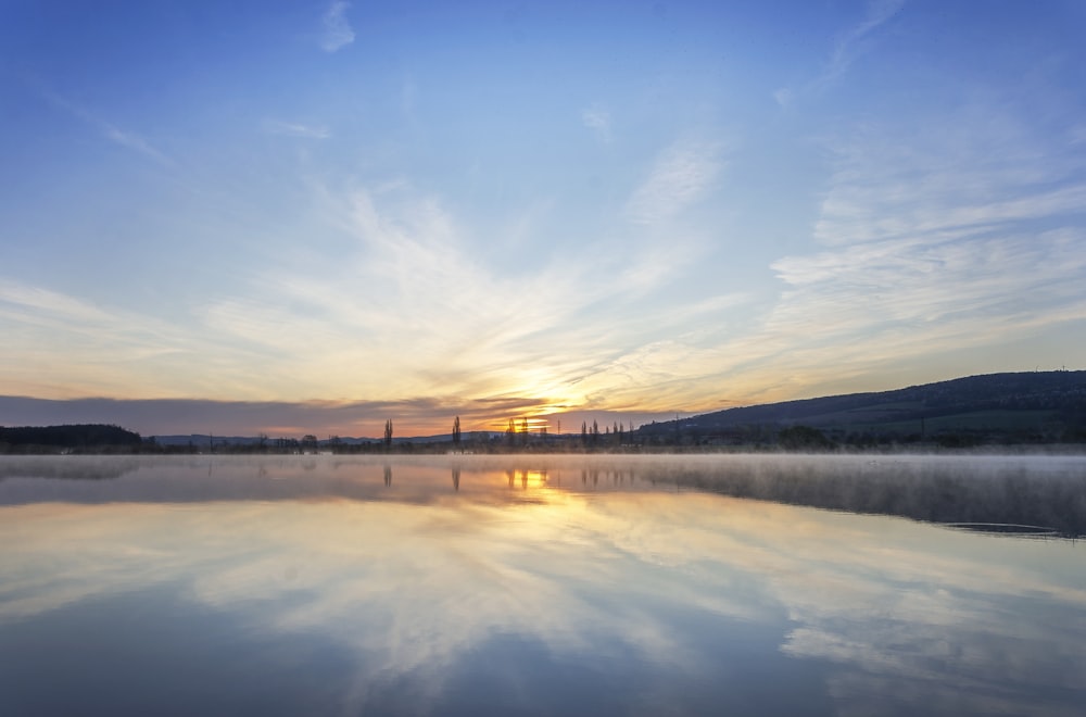 body of water near mountain under blue sky during daytime