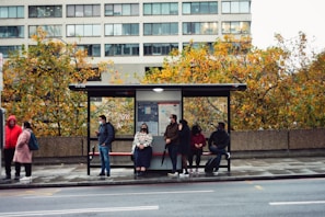 A cheerful group of people waiting at a bus stop, chatting.