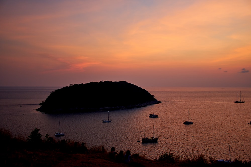 silhouette of mountain near body of water during sunset