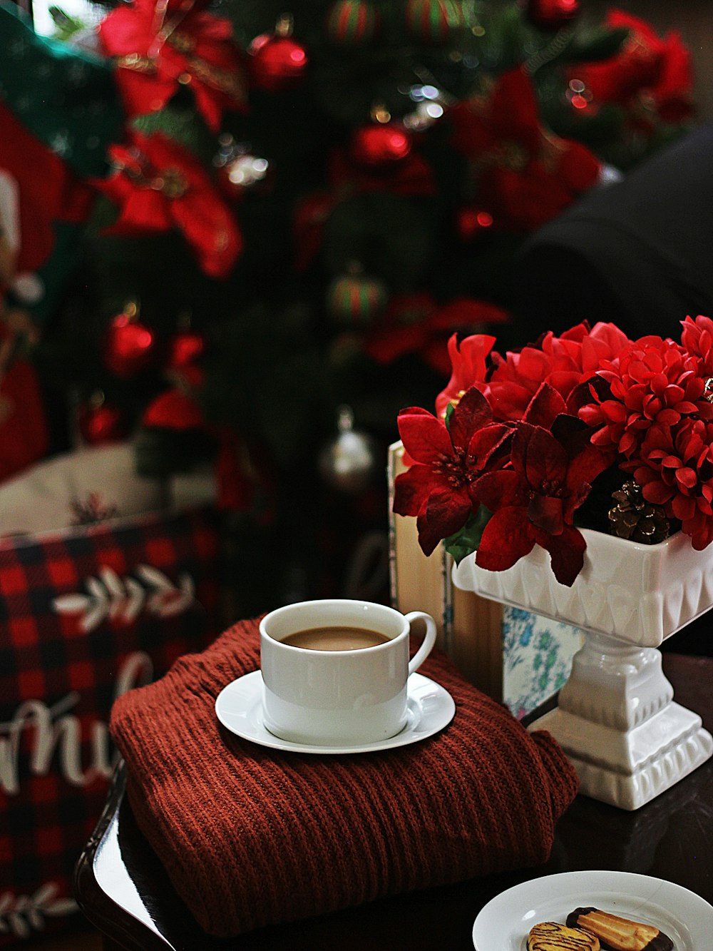 rosas rojas sobre taza de té de cerámica blanca sobre mantel a cuadros rojos y blancos