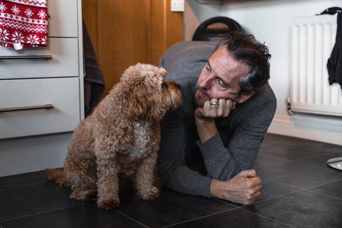 Un homme allongé face à son chien à la maison