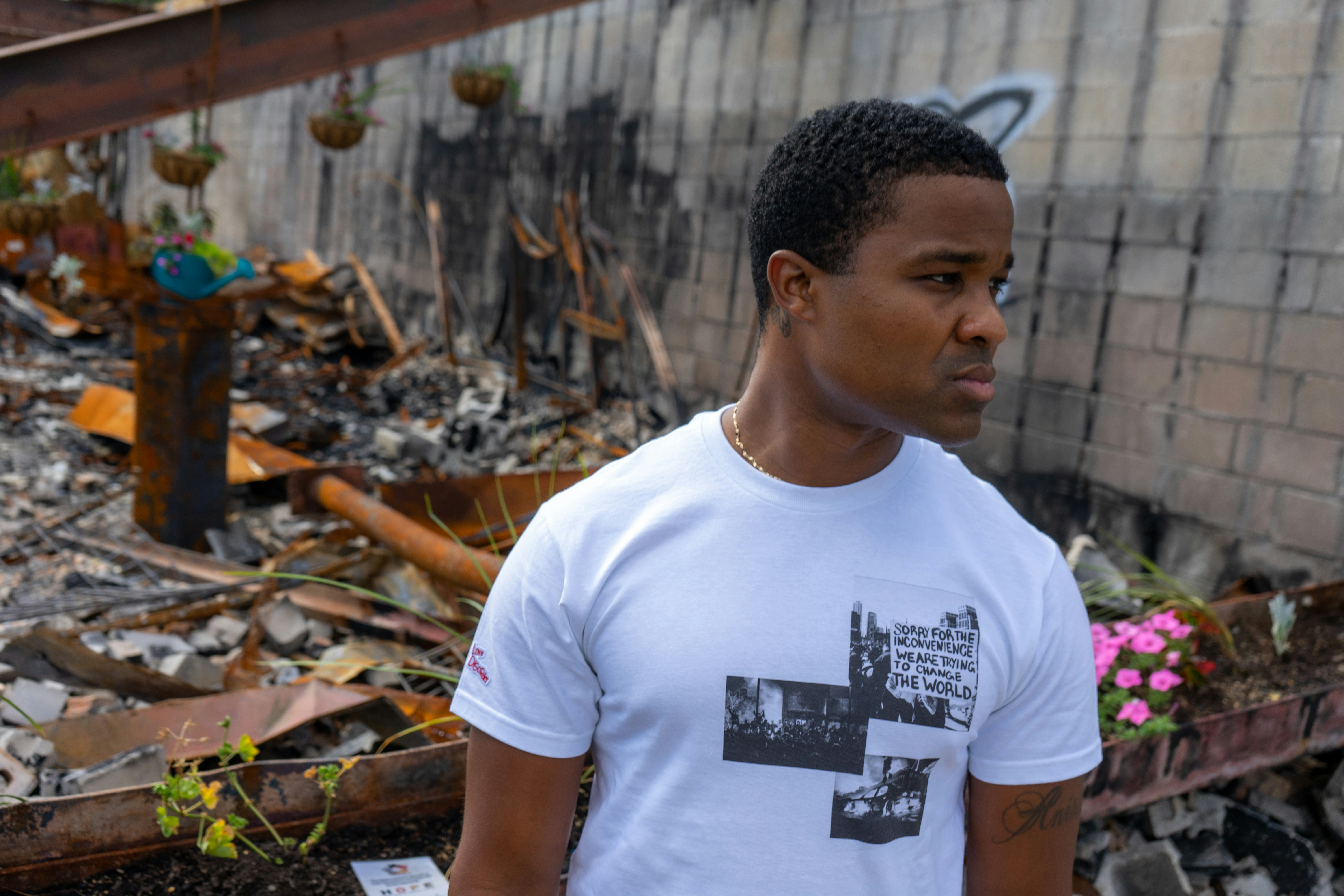 man in white crew neck t-shirt standing near brown wooden fence during daytime