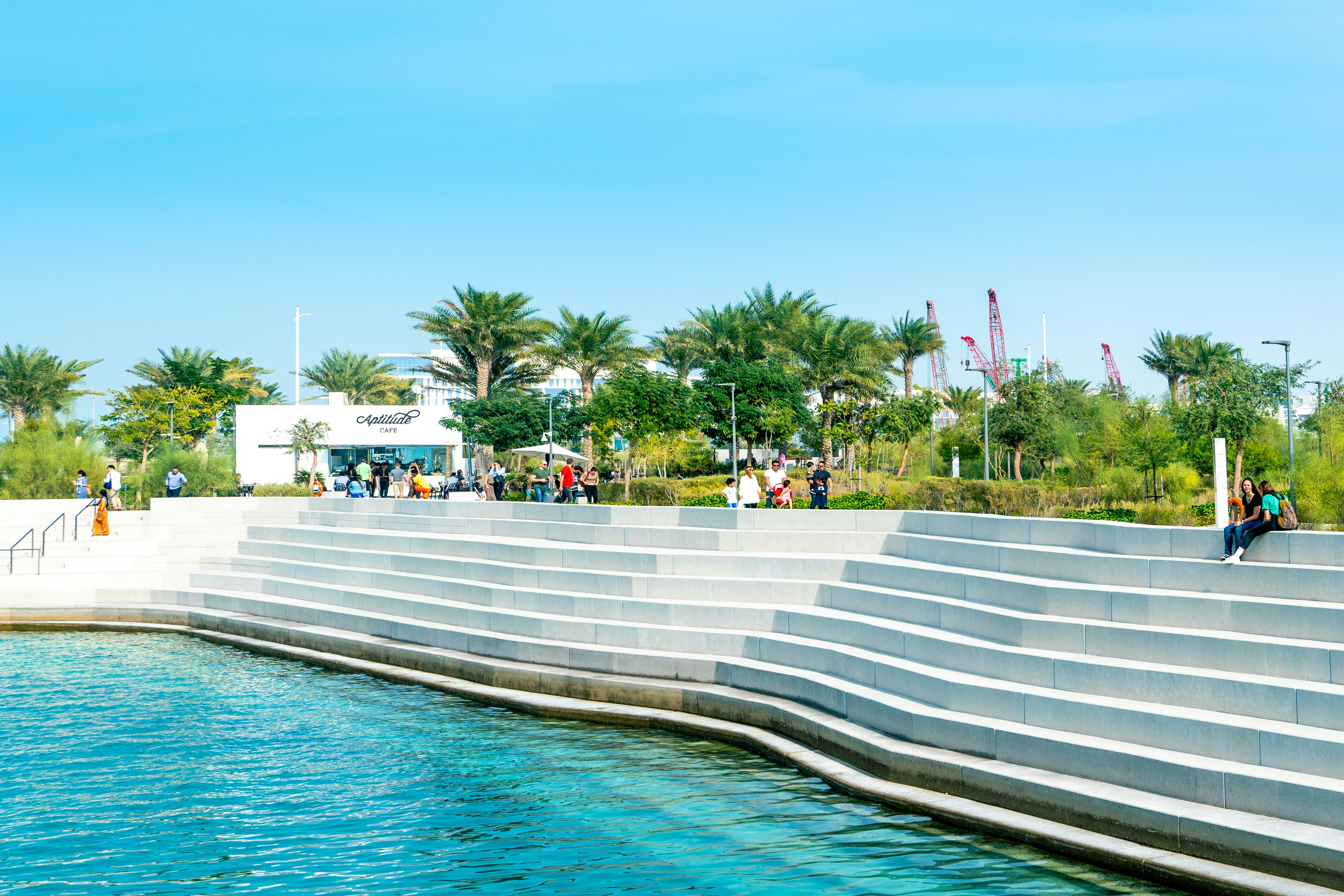 people sitting on white bench near swimming pool during daytime