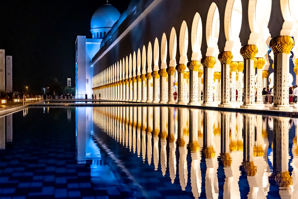 edificio in cemento bianco vicino allo specchio d'acqua durante la notte