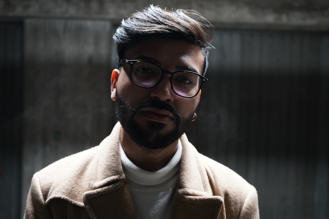 man in brown coat wearing black framed eyeglasses,