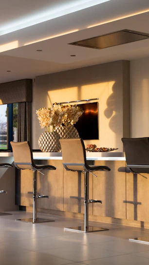 Cozy kitchen corner featuring a leather counter stool beside a rolling prep cart with natural light streaming in.