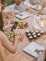 A rustic outdoor wedding buffet setup with disposable tableware and floral decorations.