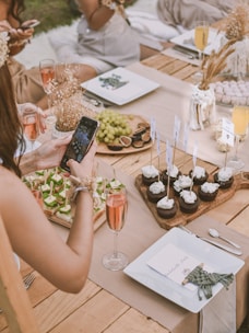 Elegant grazing table setup at an outdoor event featuring natural linen, marble accents, and an abundance of colorful, fresh ingredients.