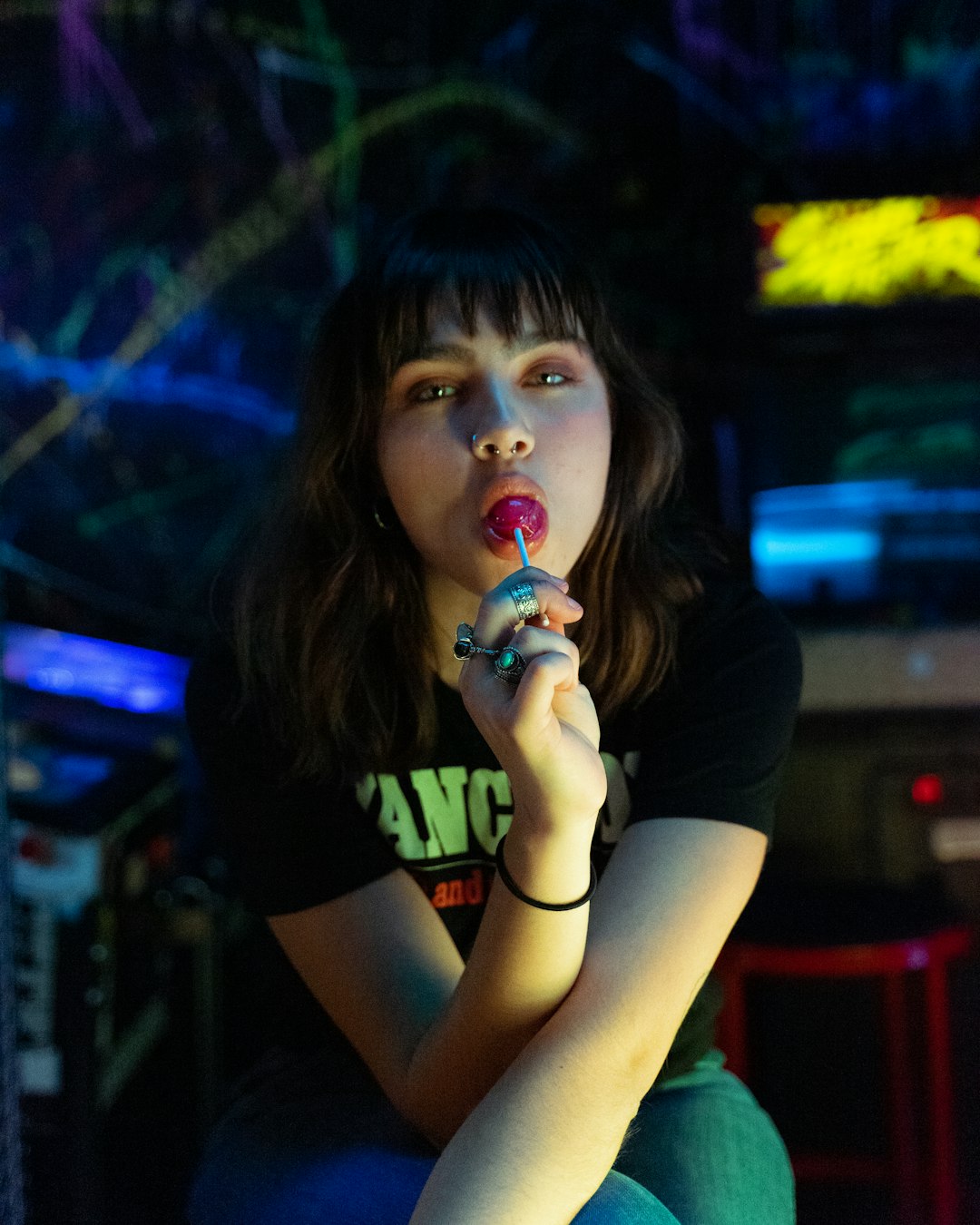 woman in black t-shirt holding red lollipop