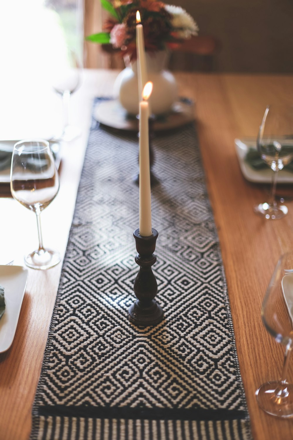 black candle holder with white candle on brown wooden table