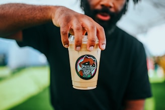 Hands holding a Dulaplast cup filled with a refreshing beverage outdoors.