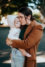 woman in brown coat hugging woman in white knit cap