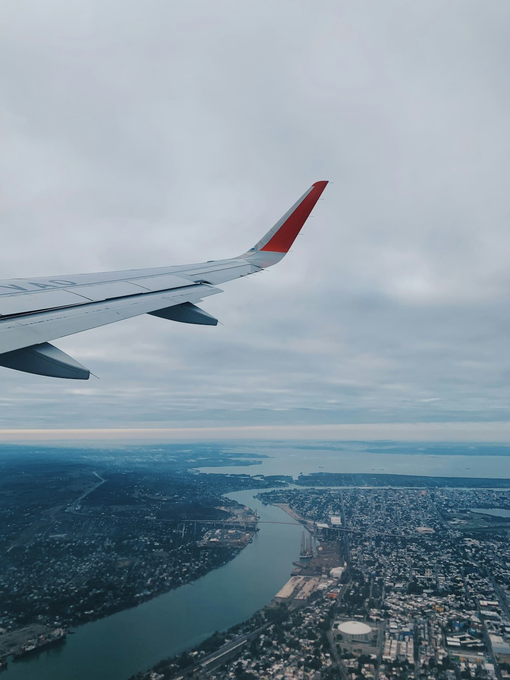 Ala de avión blanca y roja sobre la ciudad durante el día