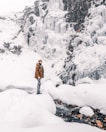 woman in brown coat standing on snow covered ground