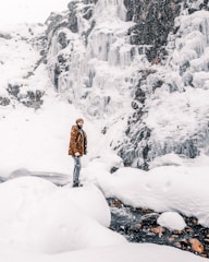 woman in brown coat standing on snow covered ground