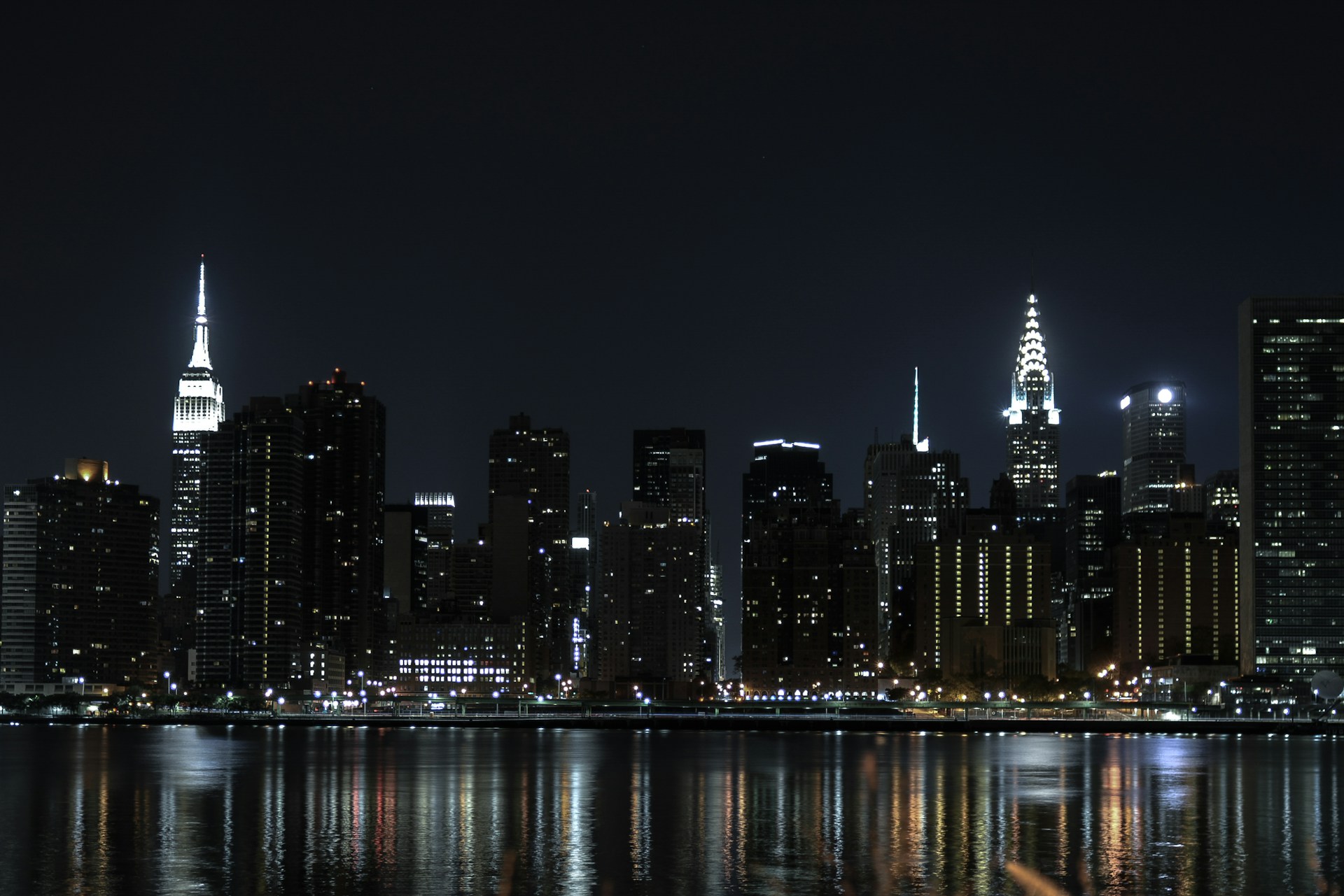 city skyline across body of water during night time