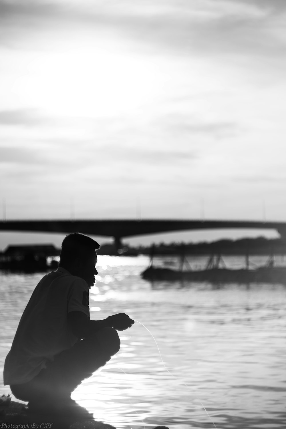 호수에서 낚시하는 남자의 그레이스케일 사진