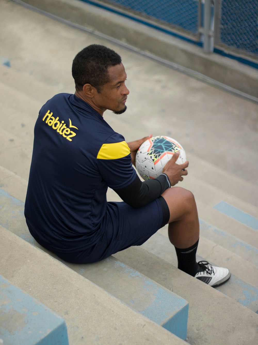 man in blue crew neck t-shirt and black shorts sitting on concrete bench