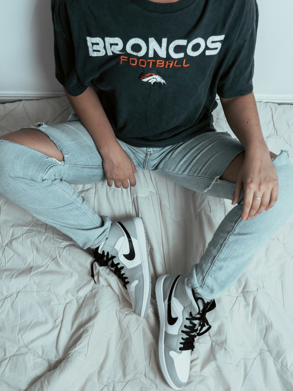 man in black crew neck t-shirt and gray denim jeans sitting on bed