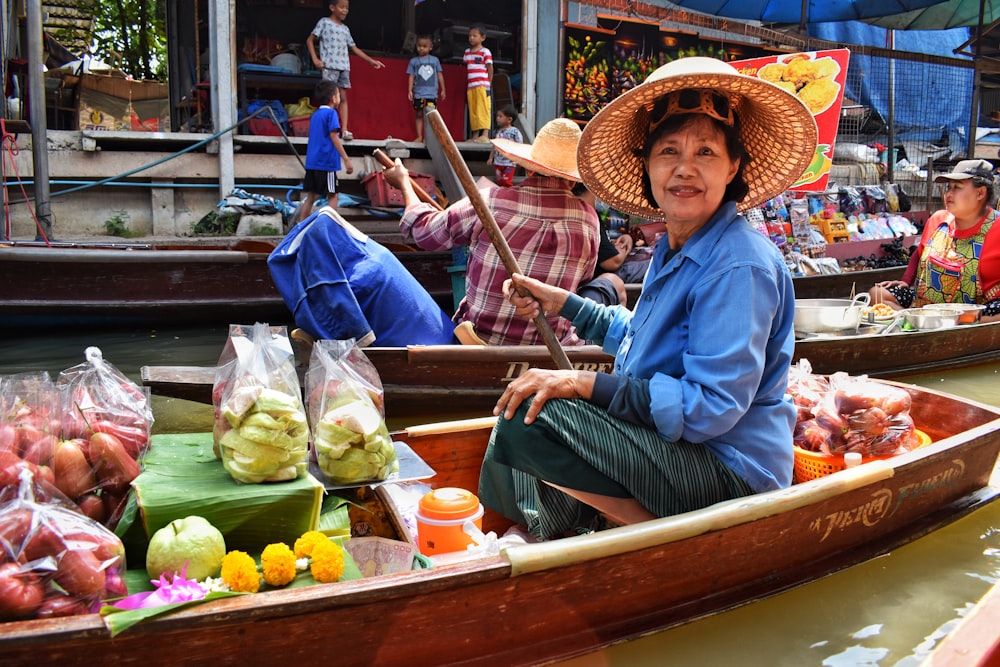 woman in blue dress shirt and brown straw hat sitting on brown wooden boat